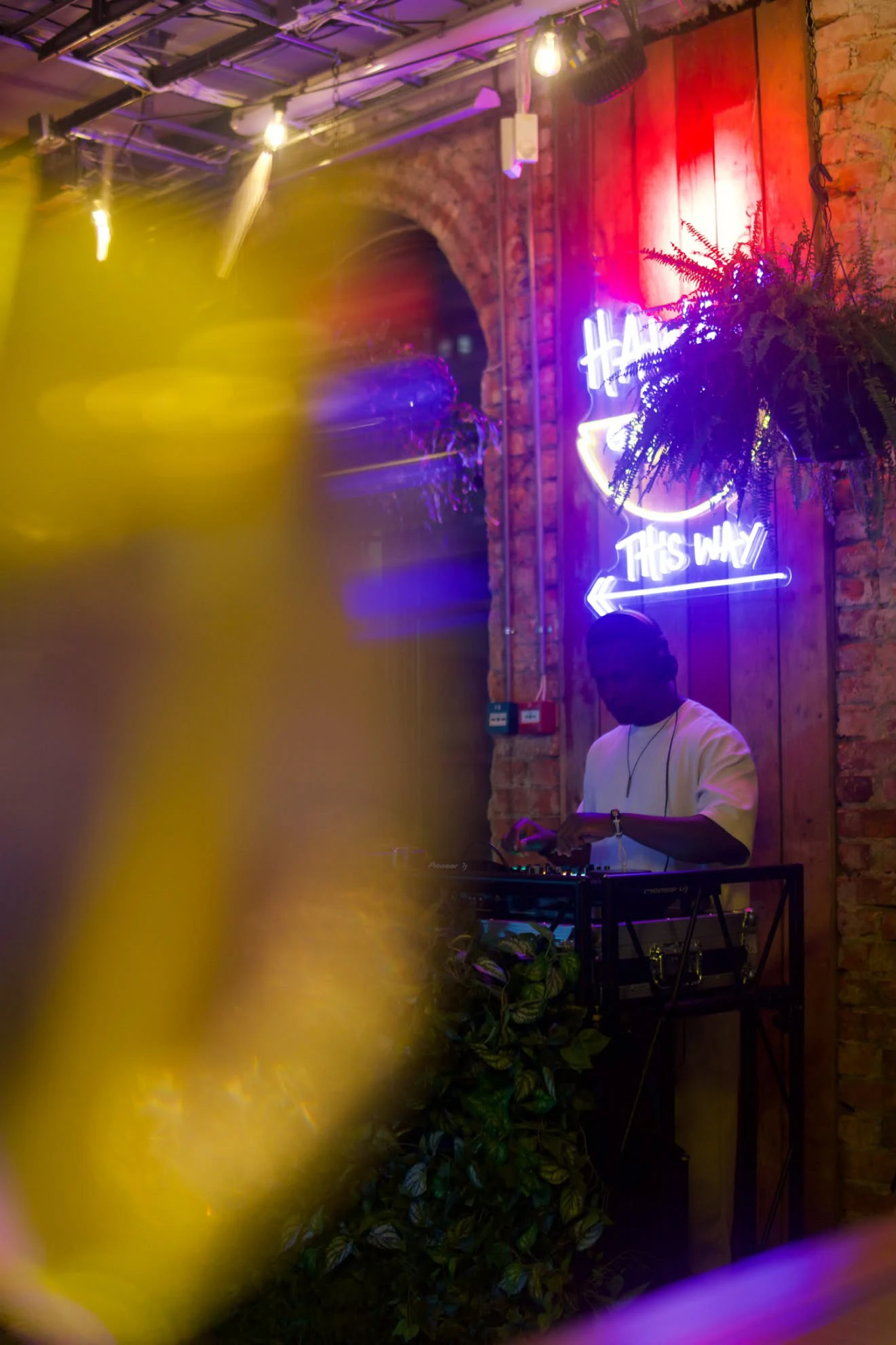 DJ fotografert gjennom gyllent lys med neon i bakgrunnen